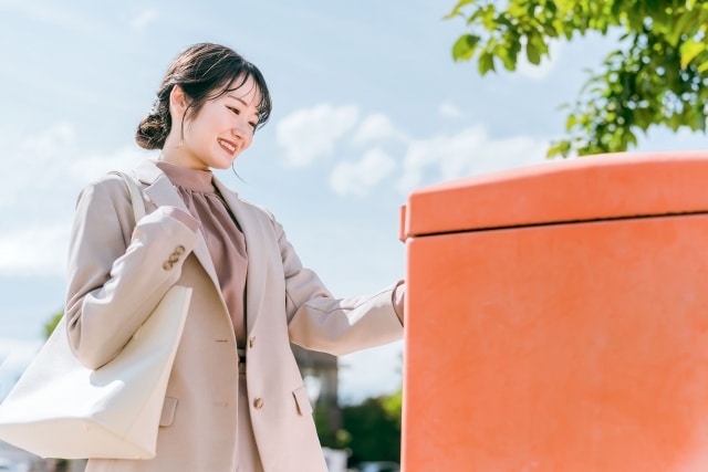 郵便ポストに手紙を入れる女性